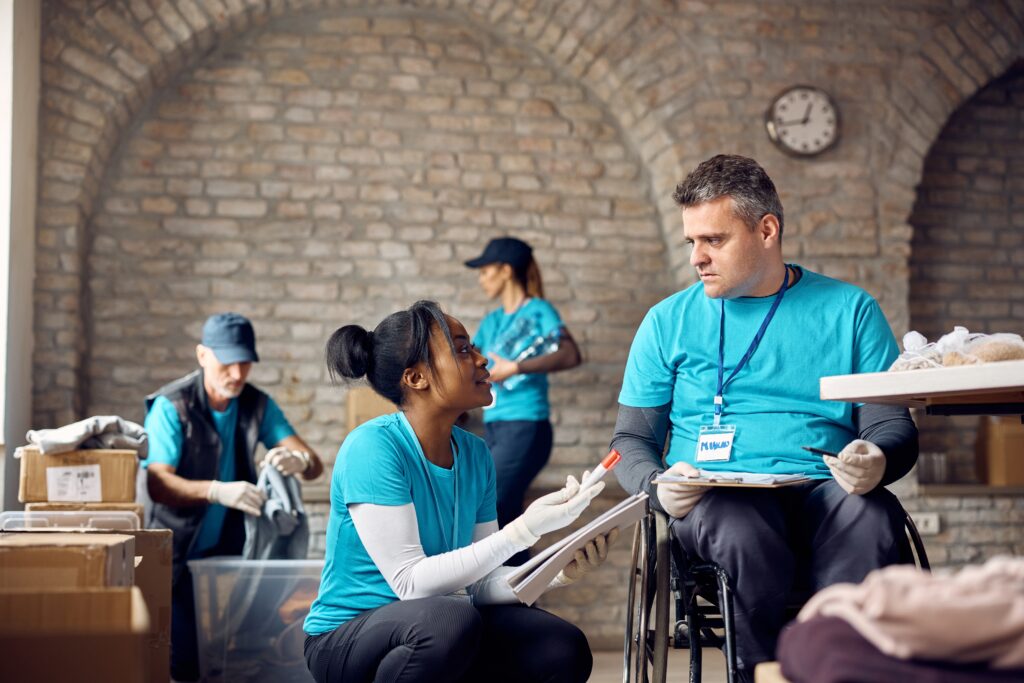 African American Volunteer Talking To,A,Coordinator,In,Wheelchair,While Lady volunteer talking to another volunteer on wheelchair